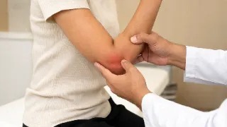 Doctor Examining Patient Elbow Joint in Clinical Consultation Photo