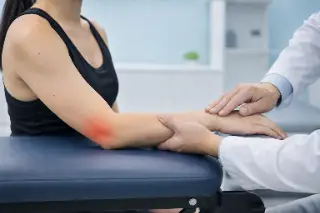 Physician Examining Patient Arm with Tennis Elbow Pain - Clinical Orthopedics Photo