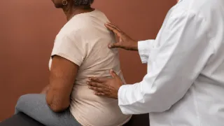 Physician Examining Patient Spine for Thoracic Kyphosis Stock Photo