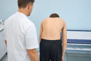 Physician Performing Scoliosis Screening Test on Adolescent Patient - Clinical Photo