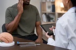 Male Patient Describing Head Pain During Neurologist Consultation - Medical Stock Photo