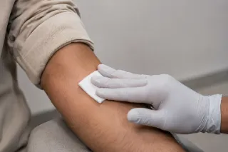 Applying Pressure With Gauze On Patient Arm After Blood Draw Stock Photo