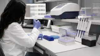 Female Molecular Scientist Pipetting Samples in Biotechnology Research Laboratory